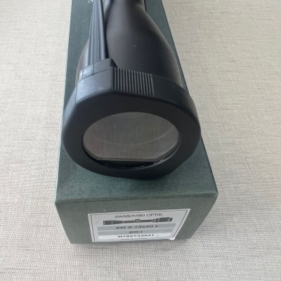 Luneta de mira telescópica preta sobre caixa verde com rótulo branco