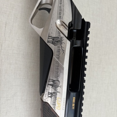 Parte de arma de fogo com detalhes em madeira, metal cinza e preto e gravação de veados e montanhas