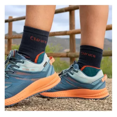 Ténis azuis com solado laranja e meias pretas com texto Chíruca, em ambiente exterior.