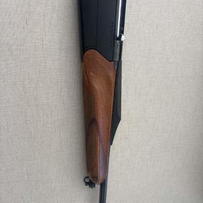 Espingarda com punho de madeira e metal preto com texto BENELLI ARMI na parede clara