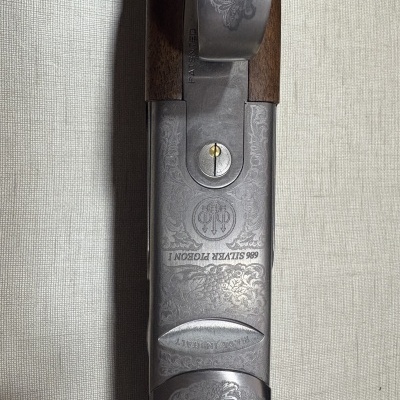 Detalhe de espingarda em metal e madeira com gravações e inscrições