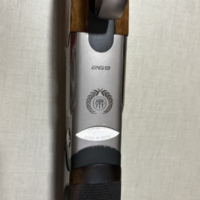 Detalhe da empunhadura e parte da arma com metal prateado e madeira escura