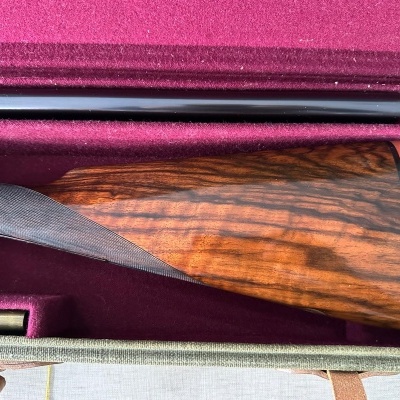 Espingarda com coronha de madeira polida em caixa forrada a veludo roxo