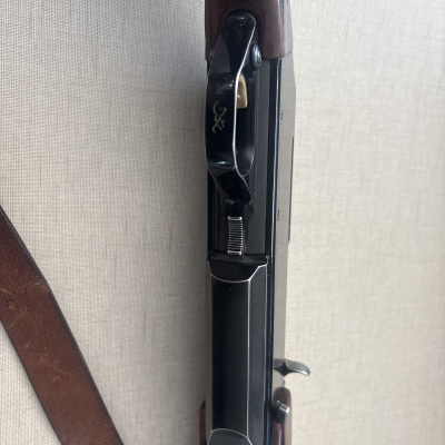 Arma de fogo com coronha de madeira castanha e mecanismo metálico negro