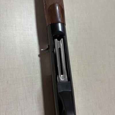 Espingarda com cabo de madeira castanha e cano metálico prateado.