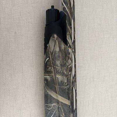 Arma de caça com padrão camuflado em cores cinza, preto e bege com textura rugosa