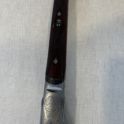 Corpo superior de arma com cabo em madeira escura e detalhes gravados em metal