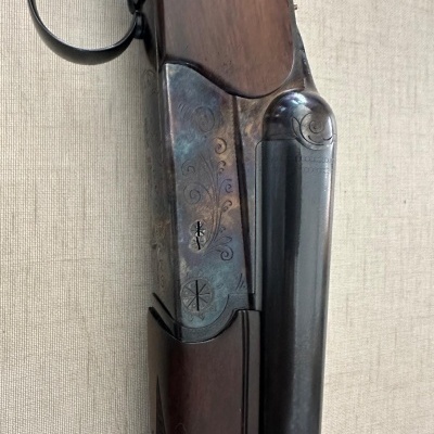 Espingarda sobreposta em madeira e metal com detalhes gravados