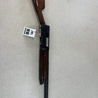 Espingarda de caça com madeira castanha e metal preto, etiqueta pendurada e fundo claro