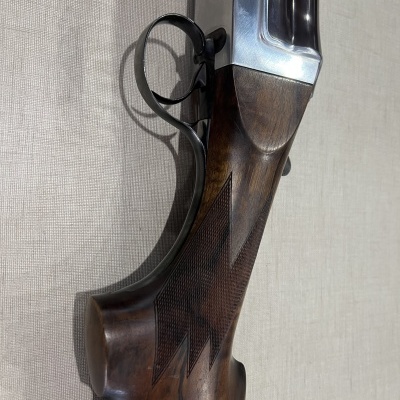 Espingarda de madeira polida com entalhes geométricos e partes metálicas prateadas