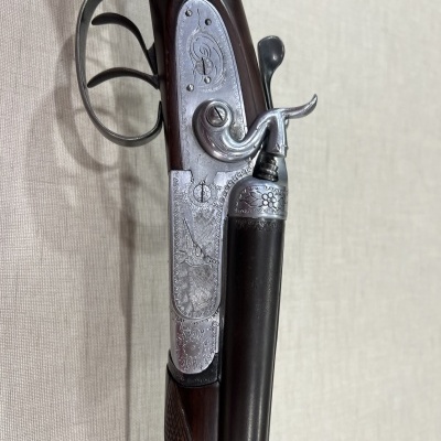 espingarda de canos duplos em madeira escura com detalhes metálicos