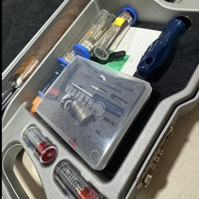 Estojo cinzento aberto com peças e ferramentas para arma de fogo com indicação BERETTA.