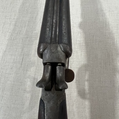 Arma de fogo antiga de cano duplo em metal escuro sobre tecido cinza