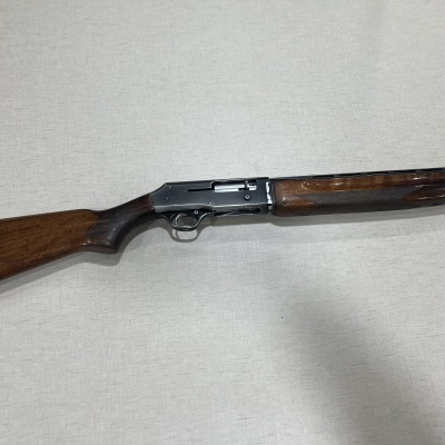 Espingarda com coronha e guarda-mão em madeira castanha e corpo metálico prateado sobre fundo cinzento