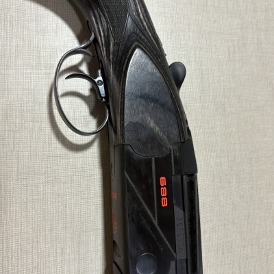 Espingarda com coronha de madeira escura e placa preta com texto 888 e BERETTA