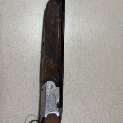 Espingarda com coronha de madeira e detalhes em metal prateado gravado