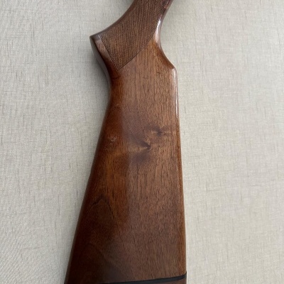 Coronha de arma de madeira castanha com padrão quadriculado e peças metálicas pretas