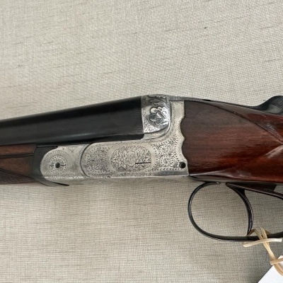Espingarda de canos duplos com detalhes em madeira e metal prateado