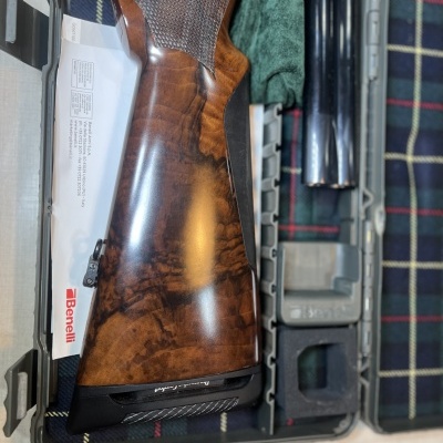 Espingarda desmontada em estojo sobre superfície xadrez