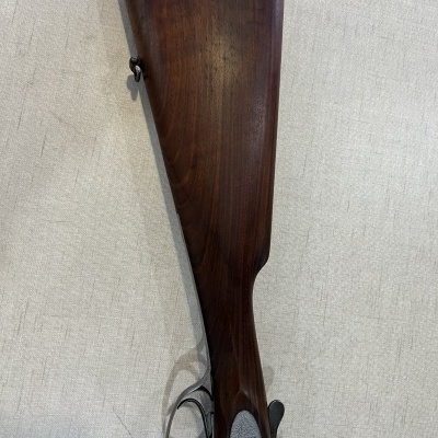Espingarda com coronha de madeira escura e detalhes metálicos