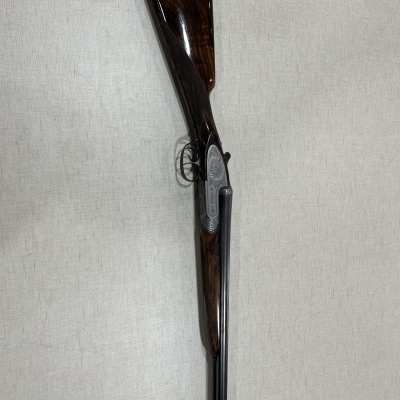 Espingarda de cano duplo com coronha em madeira escura e acabamento brilhante
