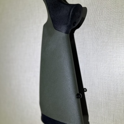 Coronha verde de carabina com detalhes pretos contra parede clara