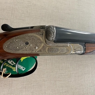 Espingarda de canos duplos em metal gravado com coronha de madeira polida