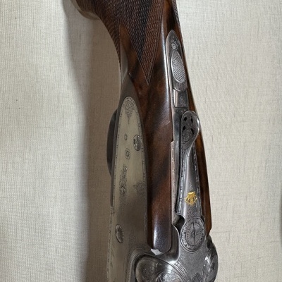 Espingarda de caça com madeira castanha e detalhes em metal gravado.