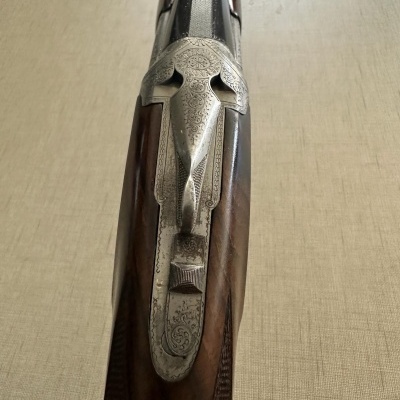 Espingarda de canos duplos com madeira polida e detalhes metálicos gravados