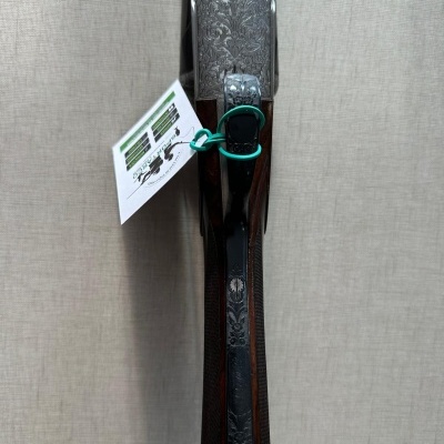 Espingarda com detalhes gravados e etiqueta pendurada numa parede clara