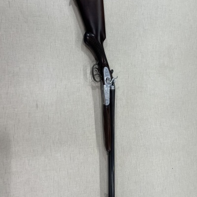 Espingarda de caça em madeira escura e metal preto com detalhes prateados