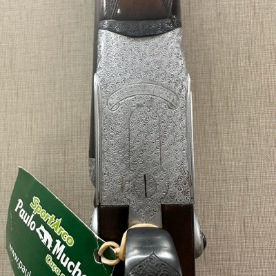 Espingarda com metal gravado e madeira escura com etiqueta verde de marca