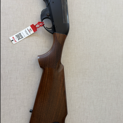 Espingarda com coronha em madeira e cabo preto com etiqueta pendurada