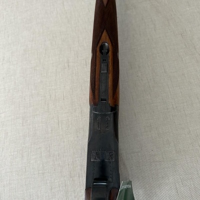 Rifle com coronha e guarda-mão em madeira castanha e metal escuro sobre tecido bege