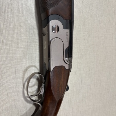 Espingarda Beretta com corpo metálico prateado e punho em madeira castanha