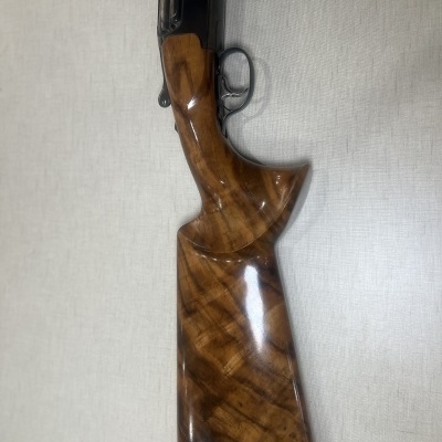 Espingarda com coronha de madeira castanha polida em superfície clara