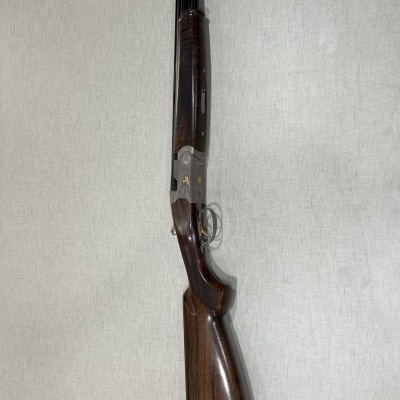 Espingarda de canos duplos com madeira castanha e metal cinza com detalhes dourados