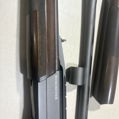 Espingarda Winchester com coronha de madeira e corpo metálico preto