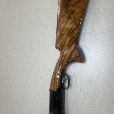 Espingarda de madeira e metal com gatilho sobre fundo cinzento claro