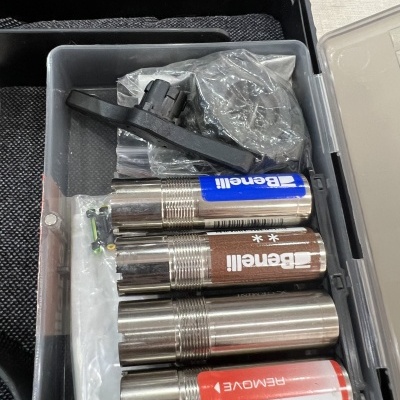 Estojo com quatro chokes metálicos para espingarda Benelli e acessórios em saco plástico.