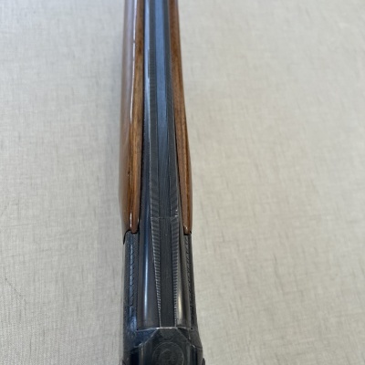 Espingarda de cano duplo com madeira castanha e metal preto gravado vista de cima