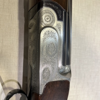 Espingarda com acabamento metálico gravado e madeira escura
