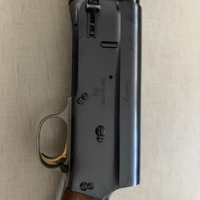 Espingarda com corpo metálico preto, gatilho dourado e madeira castanha polida