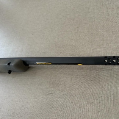 Espingarda ou carabina preta com cano longo colocada sobre superfície clara texturizada