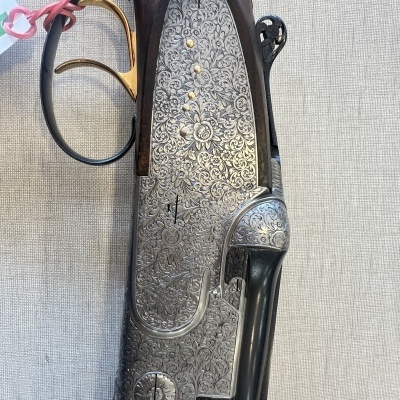 Espingarda de caça com madeira escura e detalhes metálicos gravados