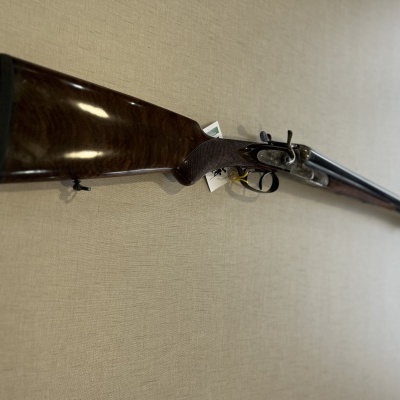 Espingarda de canos duplos com coronha em madeira castanha polida e canos longos em metal preto