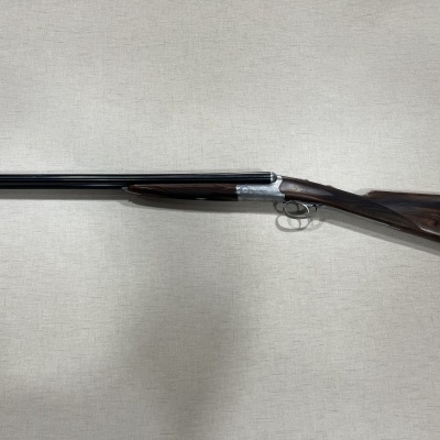 Espingarda de cano duplo com cabo em madeira escura e acabamento metálico brilhante