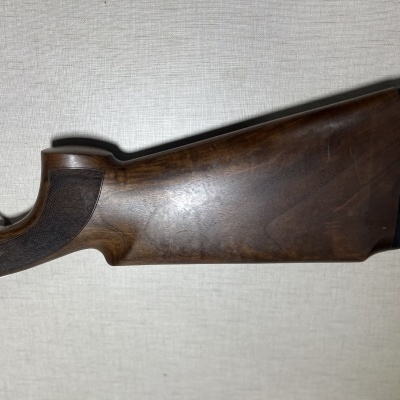 Corpo de espingarda em madeira escura com punho gravado e revestimento preto