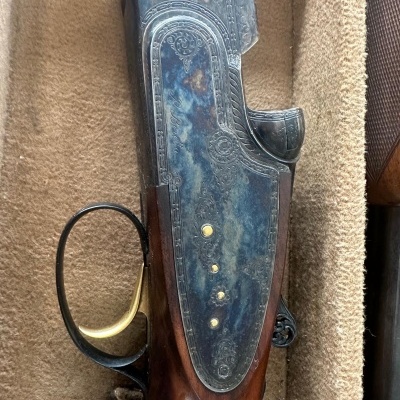 Espingarda antiga com madeira e metal gravado sobre tecido bege