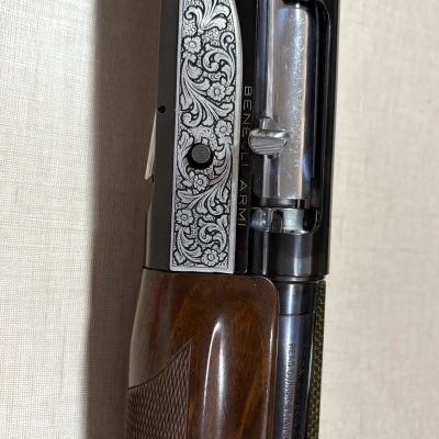 Detalhe de uma arma de fogo com gravação floral e texto BENELLI ARMI